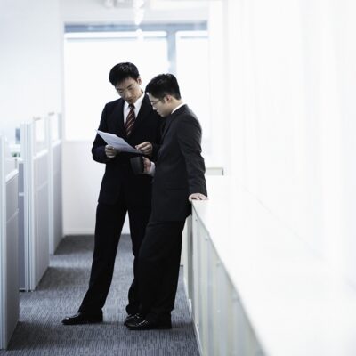 オフィスの廊下で話し合う二人のビジネスマン