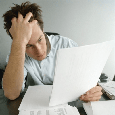 書類を見ながら頭を抱えるビジネスマン