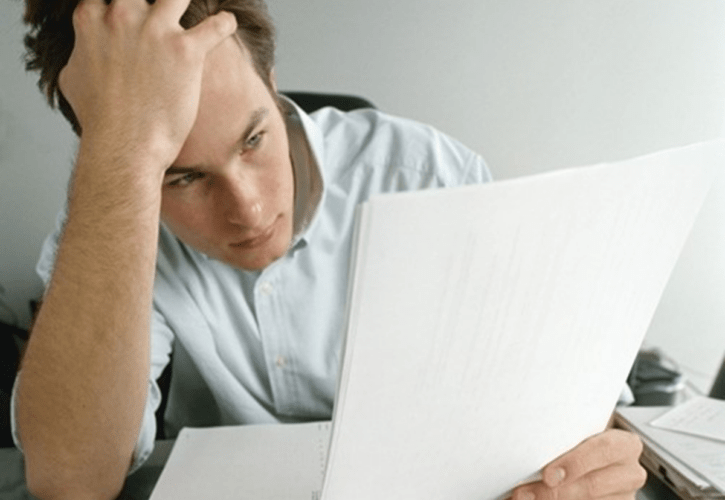 書類を見ながら頭を抱えるビジネスマン