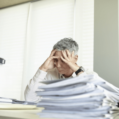 デスクで書類を見て困った様子の人