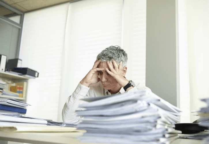 デスクで書類を見て困った様子の人